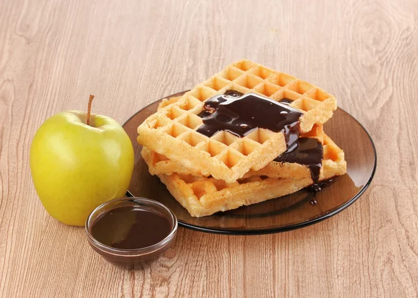 Gofres sabrosos con chocolate en plato sobre fondo de madera —  Fotos de Stock