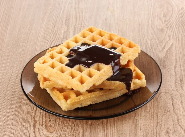 Tasty waffles with chocolate on plate on wooden background — Stock Photo, Image