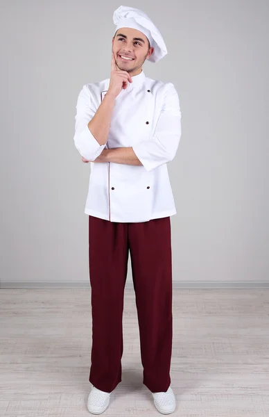 Professional chef in white uniform and hat, on gray background — Stock Photo, Image