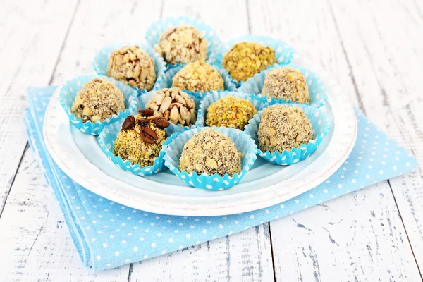 Set of chocolate candies, on plate, on wooden background — Stock Photo, Image