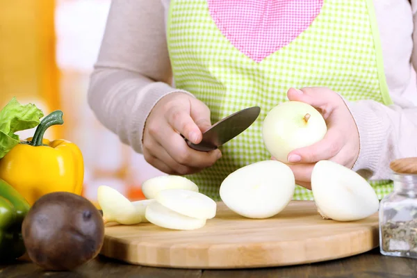 Руки женщины режут лук луковицы на кухонном фоне — стоковое фото