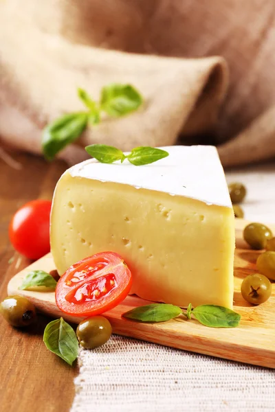 Schmackhafter Camembert-Käse mit Tomaten, Oliven und Basilikum, auf Holztisch — Stockfoto