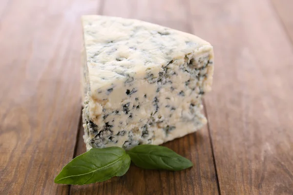 Gustoso formaggio blu con basilico, su tavola di legno — Foto Stock