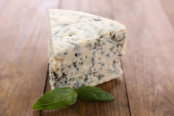 Queijo azul saboroso com manjericão, na mesa de madeira — Fotografia de Stock