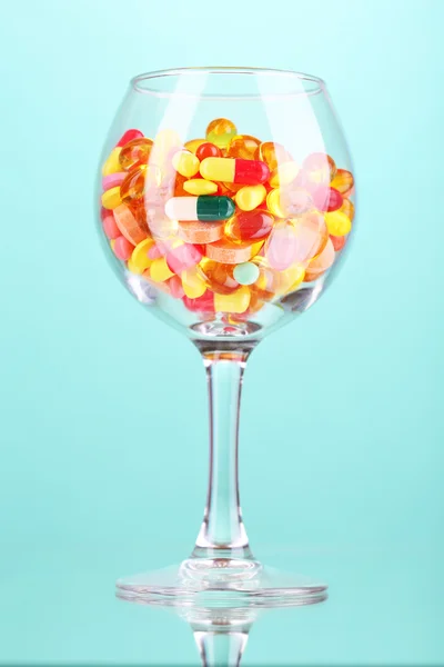 Goblet with pills on green background — Stock Photo, Image