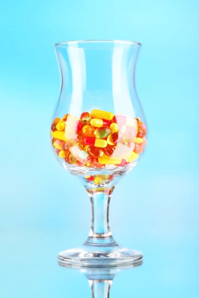 Goblet met pillen op blauwe achtergrond — Stockfoto