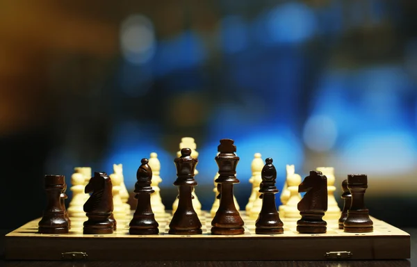 Peças de xadrez a bordo em fundo brilhante — Fotografia de Stock