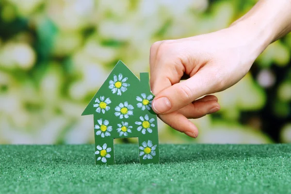 Little paper house in hand on green grass on bright background — Stock Photo, Image