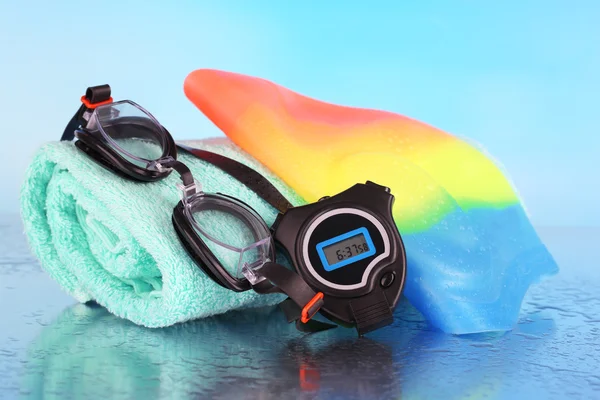 För pool: simma cap, skyddsglasögon och handduk på blå bakgrund — Stockfoto