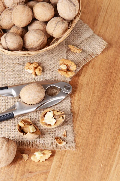 Louskáček s vlašskými ořechy na dřevěném pozadí — Stock fotografie