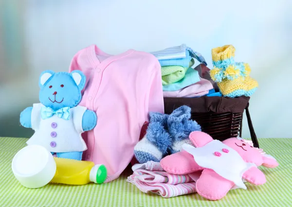 Montón de ropa de bebé en la cesta, en la mesa sobre fondo de color — Foto de Stock