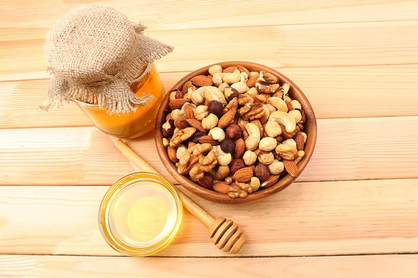 Sweet honey and different nuts on wooden table — Stock Photo, Image