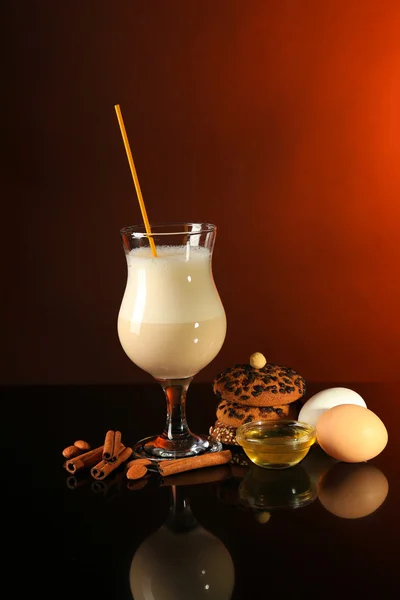 蛋奶酒含有香料和彩色背景上的橙色 — 图库照片