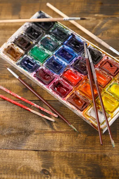 Farbenfrohe Aquarelle und Pinsel auf Holzgrund — Stockfoto