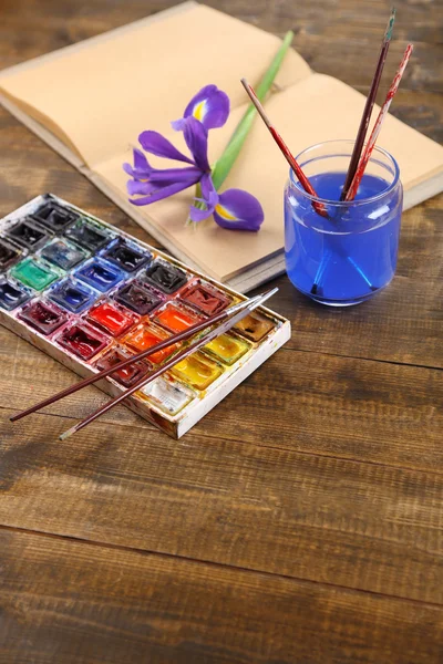 Composizione con acquerelli colorati, pennelli e bozzetto su fondo in legno — Foto Stock