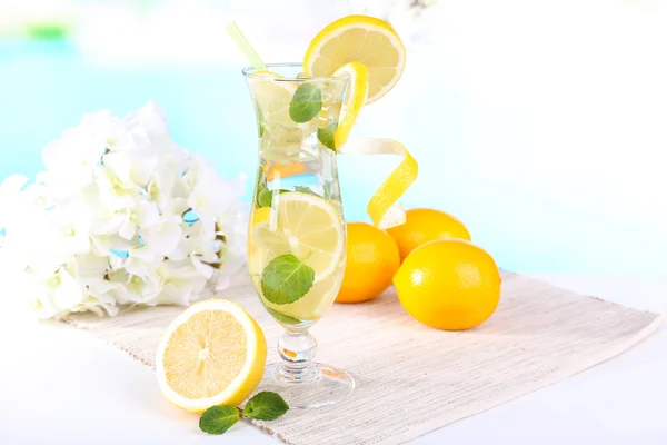 Glas Cocktail mit Zitrone und Minze auf Tisch auf hellblauem Hintergrund — Stockfoto