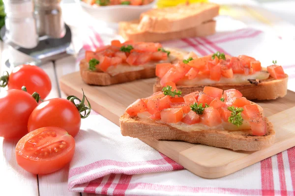 Pyszne bruschetta z pomidorami na desce do krojenia zbliżenie — Zdjęcie stockowe