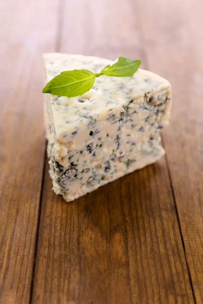 Tasty blue cheese with basil, on wooden table — Stock Photo, Image