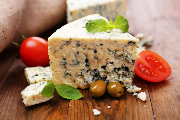 Sabroso queso azul con tomate, aceitunas y albahaca, sobre mesa de madera —  Fotos de Stock