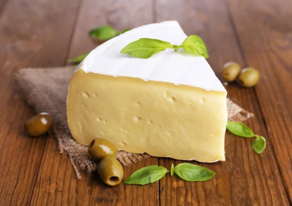 Savoureux fromage Camembert au basilic et olives, sur table en bois — Photo