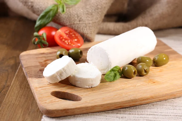 Queijo saboroso com tomate, azeitonas e manjericão, sobre tábua de corte — Fotografia de Stock