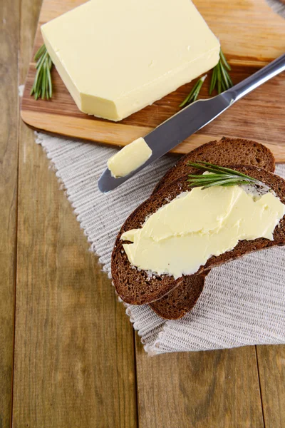 Rebanada de pan de centeno con mantequilla en tabla de cortar de madera —  Fotos de Stock