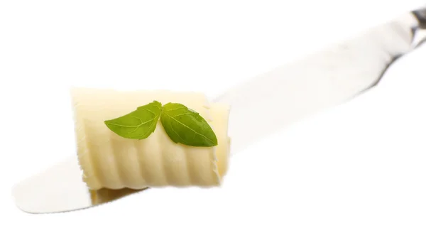 Curl of fresh butter with basil on knife, isolated on white — Stock Photo, Image