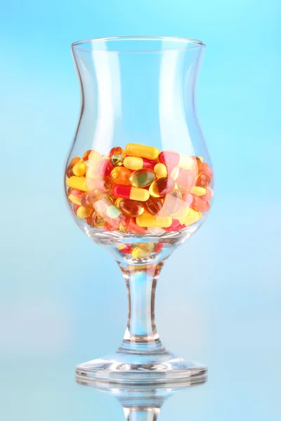 Goblet with pills on blue background — Stock Photo, Image