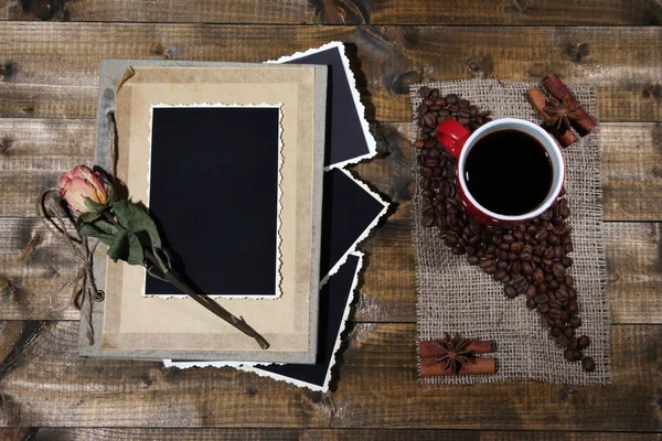 Композиция с чашкой кофе и фотоальбомом, на деревянном фоне — стоковое фото