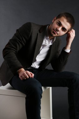 küp koyu arka plan üzerinde otururken yakışıklı genç