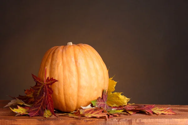Dojrzałe dynia i liści jesienią na drewnianym stole na brązowy deseń — Zdjęcie stockowe