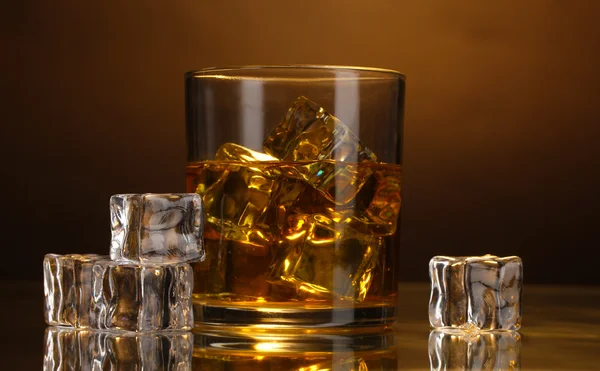 Glass of whiskey and ice on brown background — Stock Photo, Image