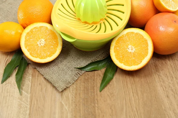 Citrus press and fruits on wooden background — Stock Photo, Image