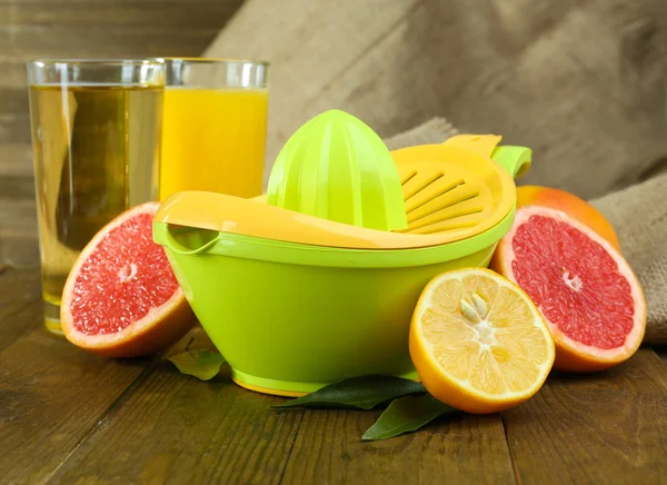 Citrus press and fruits on table on wooden background — Stock Photo, Image