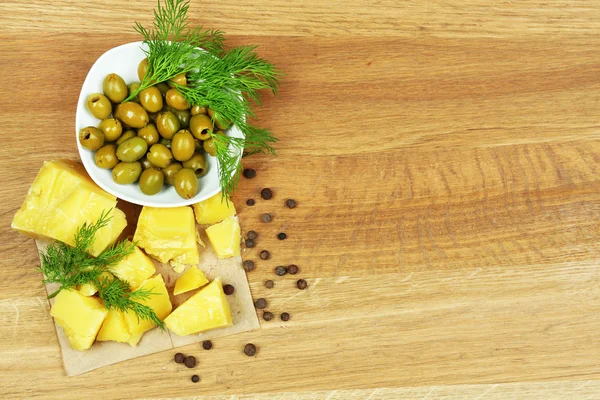 Parmesan, frische Kräuter und Oliven auf Holzgrund — Stockfoto