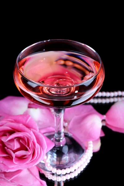 Σύνθεση με ροζ λάμψη κρασί σε ποτήρι και τριαντάφυλλο που απομονώνονται σε μαύρο — Φωτογραφία Αρχείου
