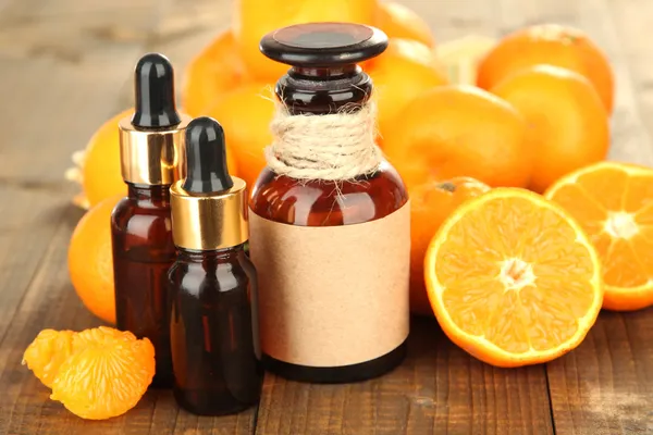 Tangerine essential oil and tangerines on wooden table — Stock Photo, Image
