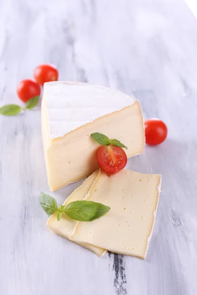 Schmackhafter Camembert-Käse mit Tomate und Basilikum, auf Holztisch — Stockfoto