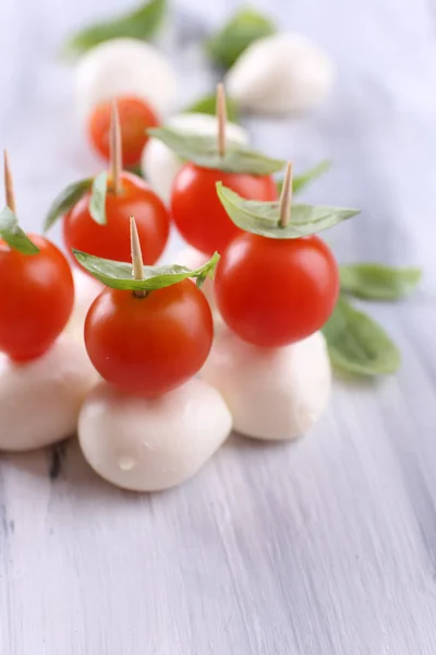 Välsmakande mozzarellaost med basilika och tomater, på träbord — Stockfoto