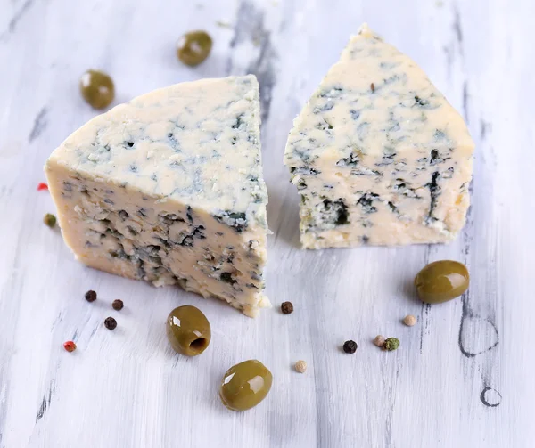 Smakelijke blauwe kaas met olijven op houten tafel — Stockfoto