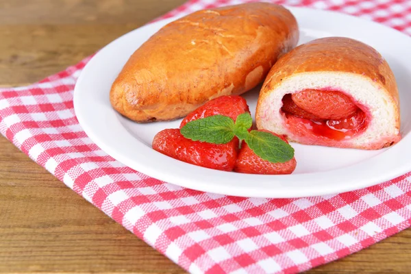 Fresh baked pasties with strawberries on plate on table close-up — Stock Photo, Image