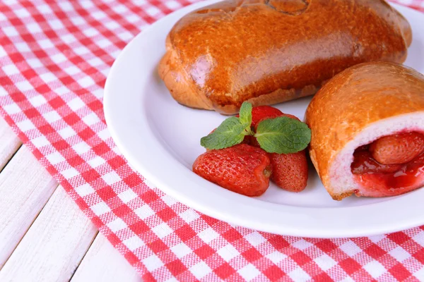 Vers gebakken pasteitjes met aardbeien op de plaat op tabel close-up — Stockfoto