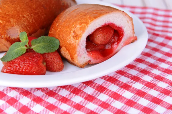 Fresh baked pasties with strawberries on plate on table close-up — Stock Photo, Image