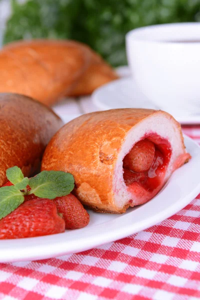 Vers gebakken pasteitjes met aardbeien op de plaat op tabel close-up — Stockfoto