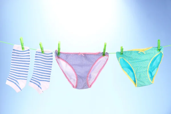 Baby clothes hanging on clothesline, on bright background — Stock Photo, Image