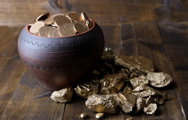 Золотые монеты в керамическом горшке и золотых монет, на деревянном фоне — стоковое фото