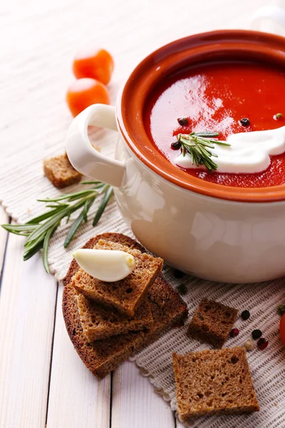 Smakelijke tomatensoep en groenten op houten tafel — Stockfoto