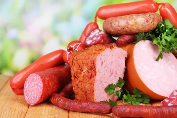Lot of different sausages on wooden table on natural background — Stock Photo, Image