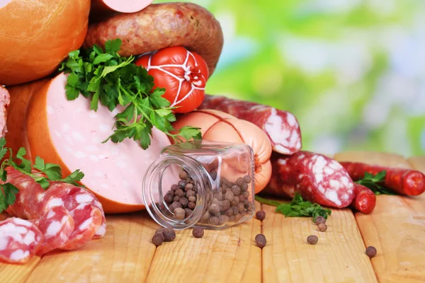 Lot of different sausages on wooden table on natural background — Stock Photo, Image