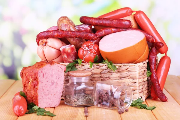 Beaucoup de différentes saucisses dans le panier sur une table en bois sur fond naturel — Photo